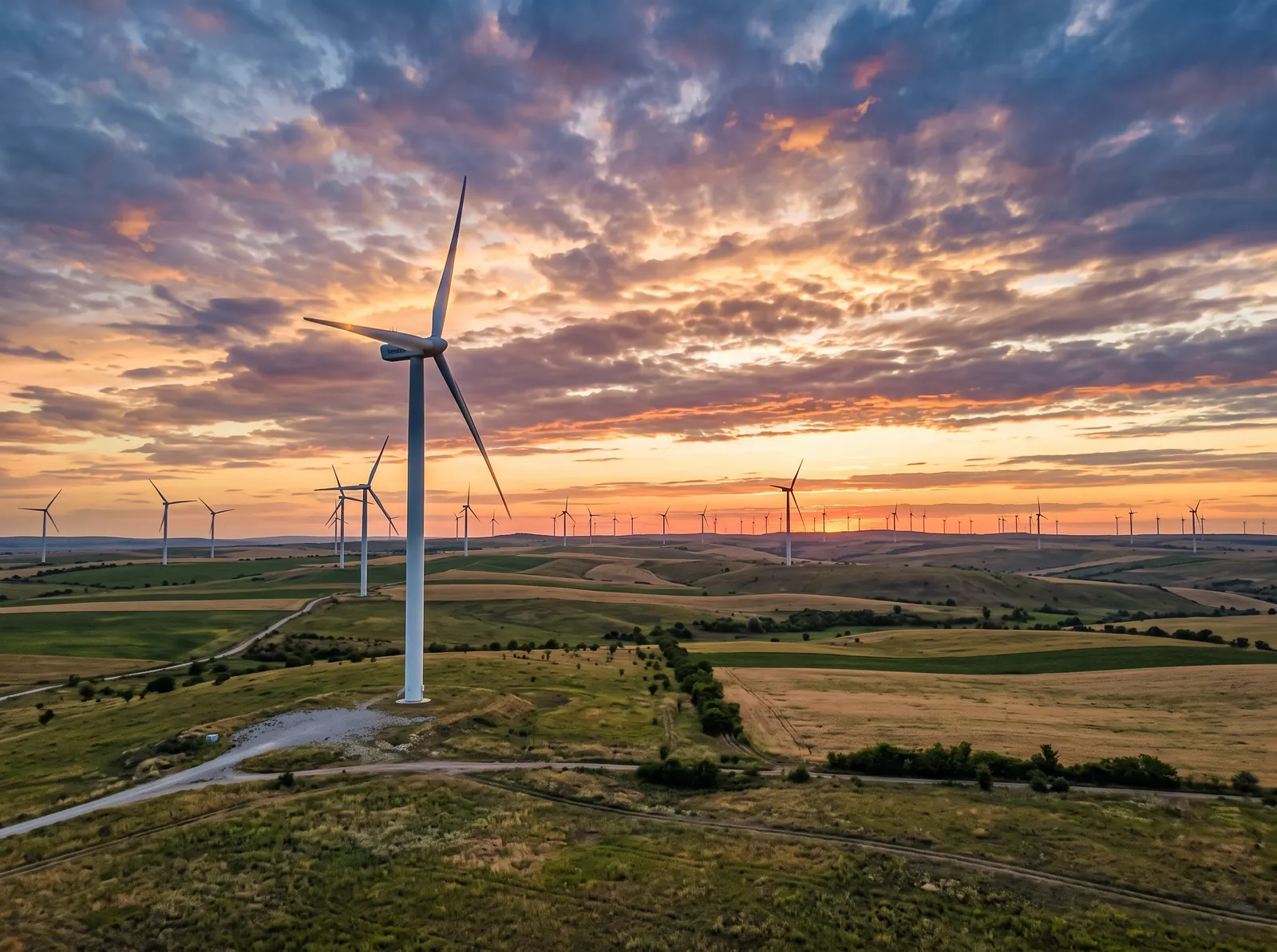 Modern onshore wind turbines across open terrain in Tulcea County at sunset